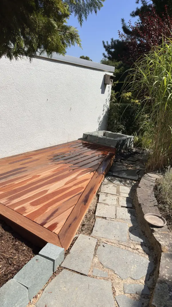 Neue Holzterrasse mit Weg aus Natursteinplatten und Einfassung